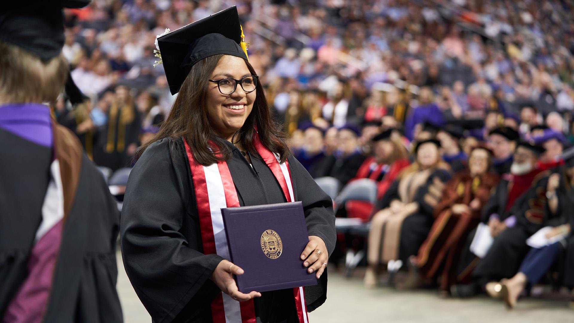 UE graduate with diploma at commencement